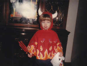 A young child dressed in a red devil costume with orange and yellow flames for Halloween